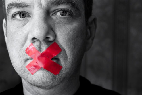 Man in Black and White With Red Tape in an "X" Over His Mouth