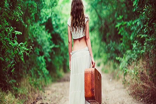 Young Woman With Suitcase in Hand Going Away On A Rural Road