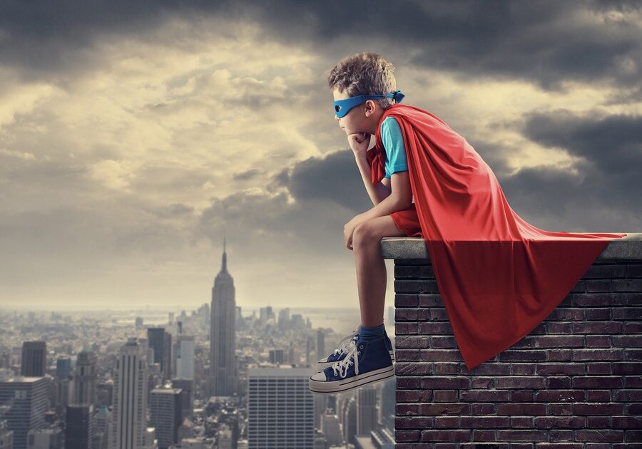 Boy in Superhero Outfit Sitting on a Roof Overlooking A City