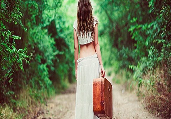 Young Woman With Suitcase in Hand Going Away On A Rural Road